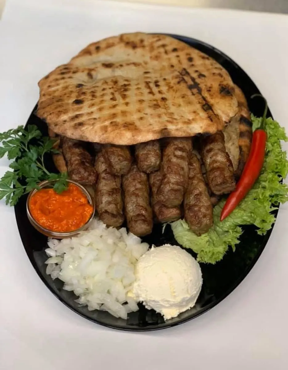 Cevapcici mit Fladenbrot, Ajvar, Zwiebeln und Kajmak