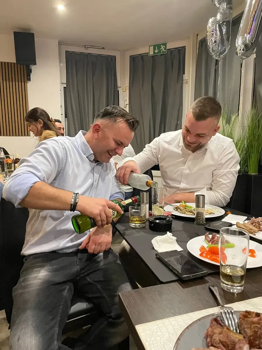 Gäste beim gemeinsamen Abendessen und Anstoßen im Gastraum