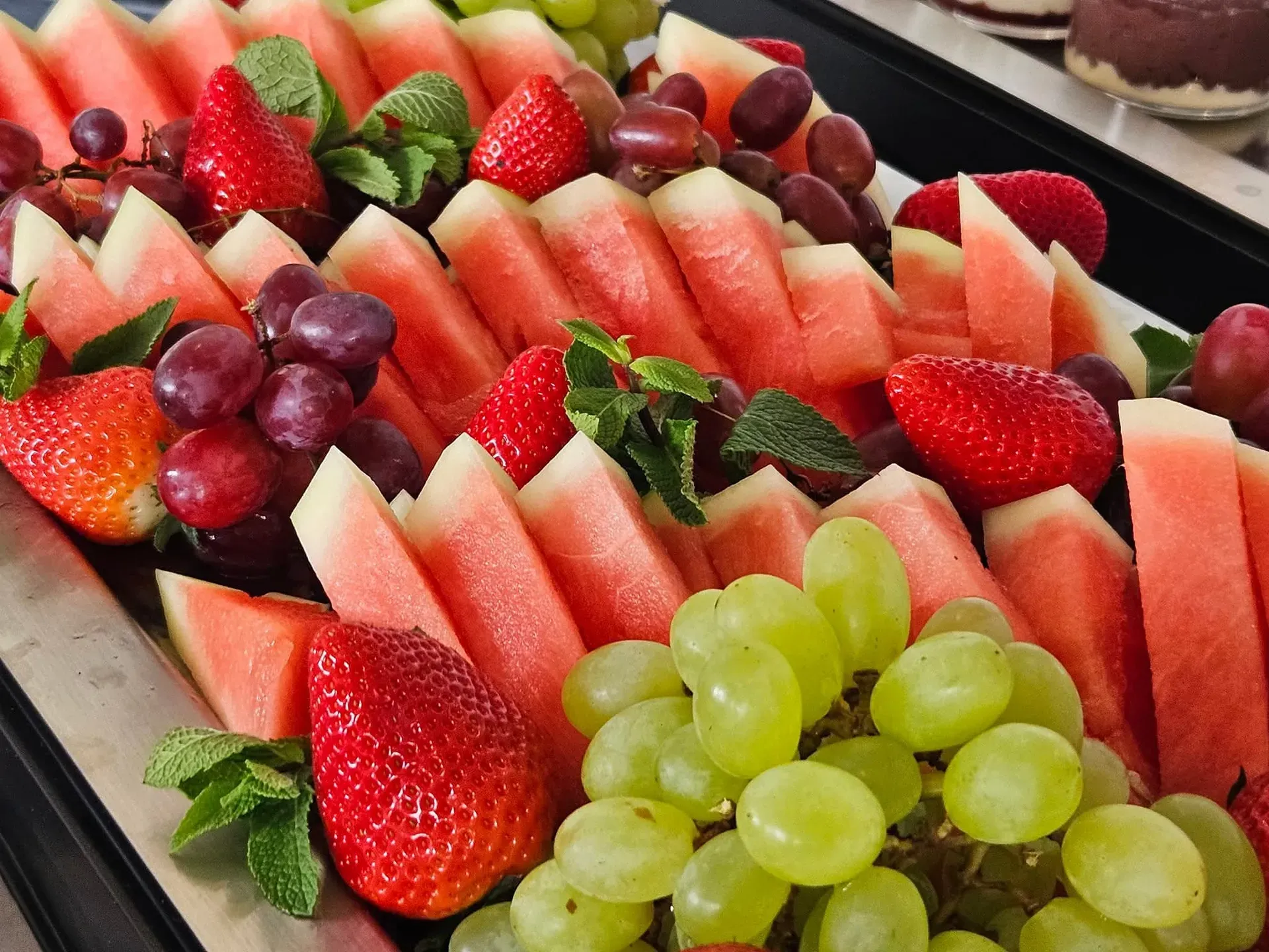 Obstplatte mit Wassermelone, Erdbeeren, Trauben und Minze